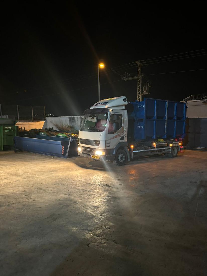משאית DAF עם מכולה כחולה במגרש בשעת לילה